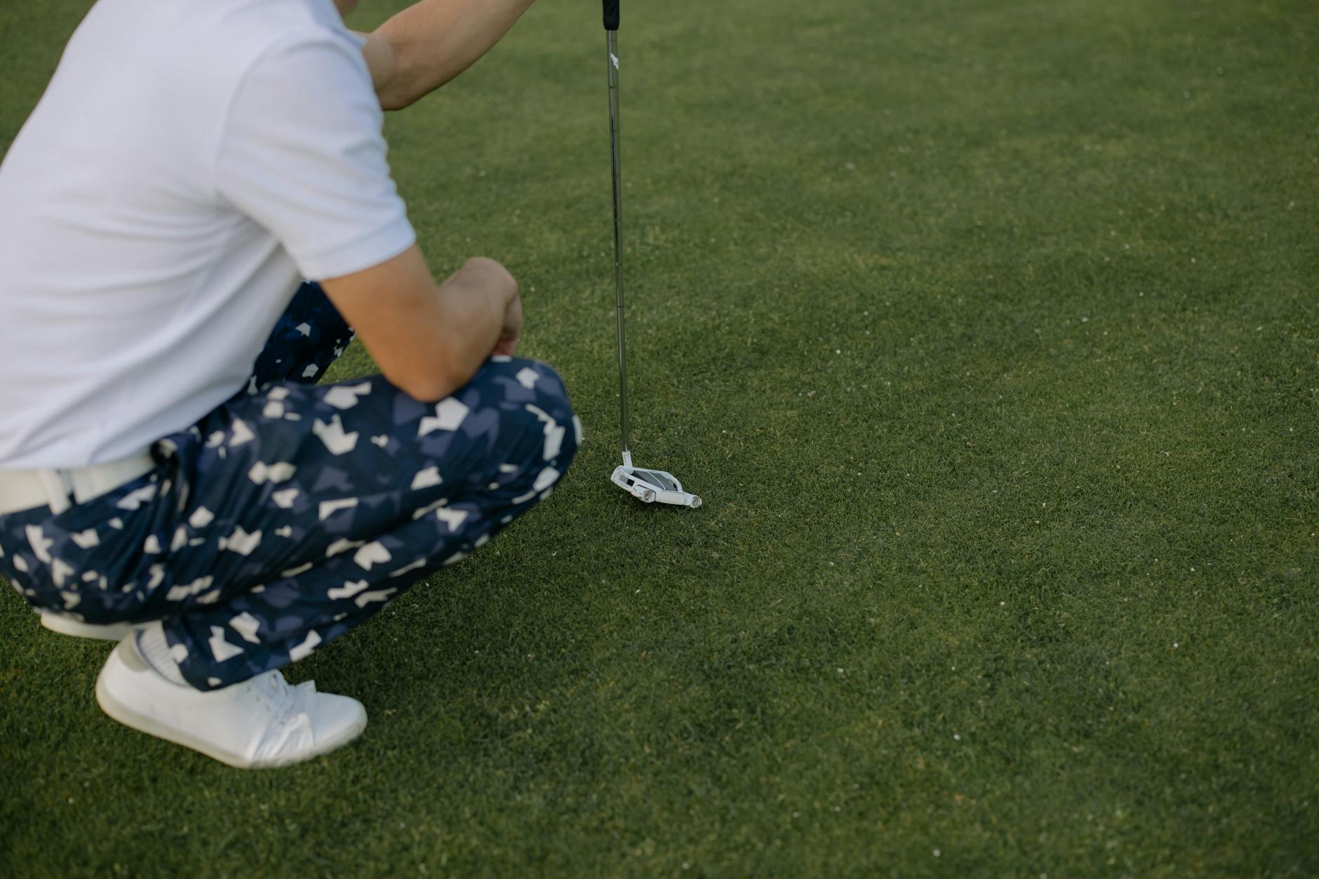 Golfer crouching on the green carefully studying the line before putting
