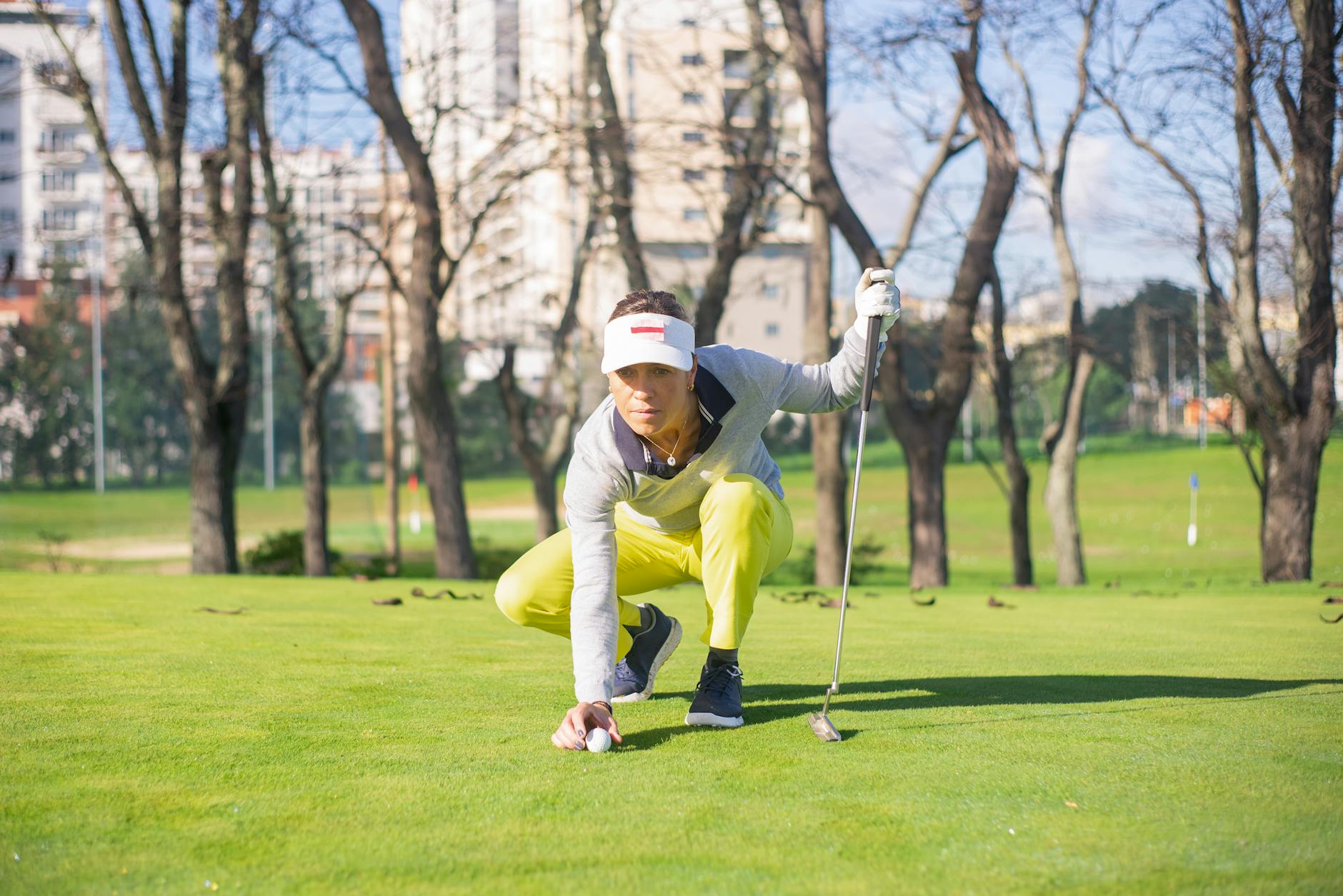 Woman golfer focusing carefully before making a putt on a sunny golf course
