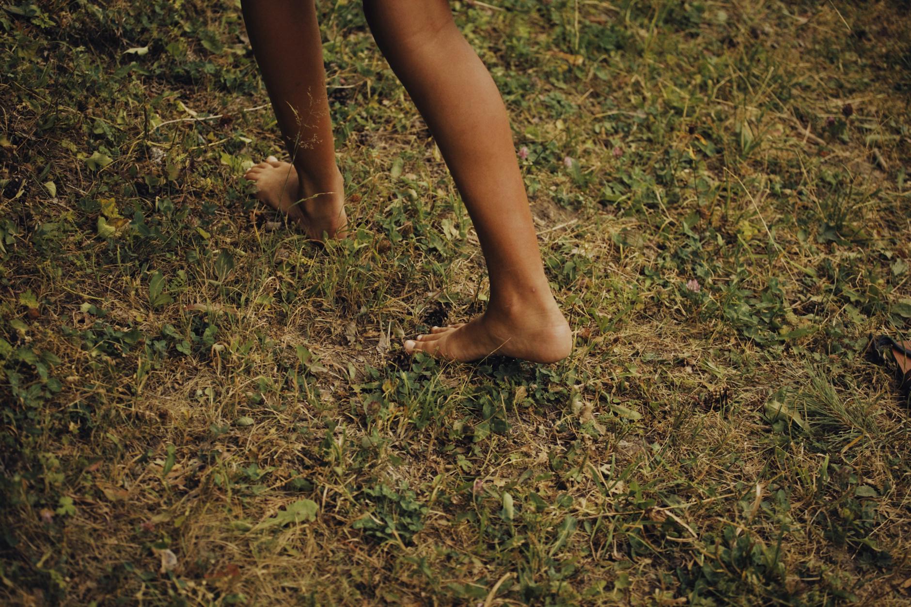 Barefoot Training Benefits for Foot Strength Close-up of bare feet walking on grass, illustrating barefoot training benefits for foot muscle development