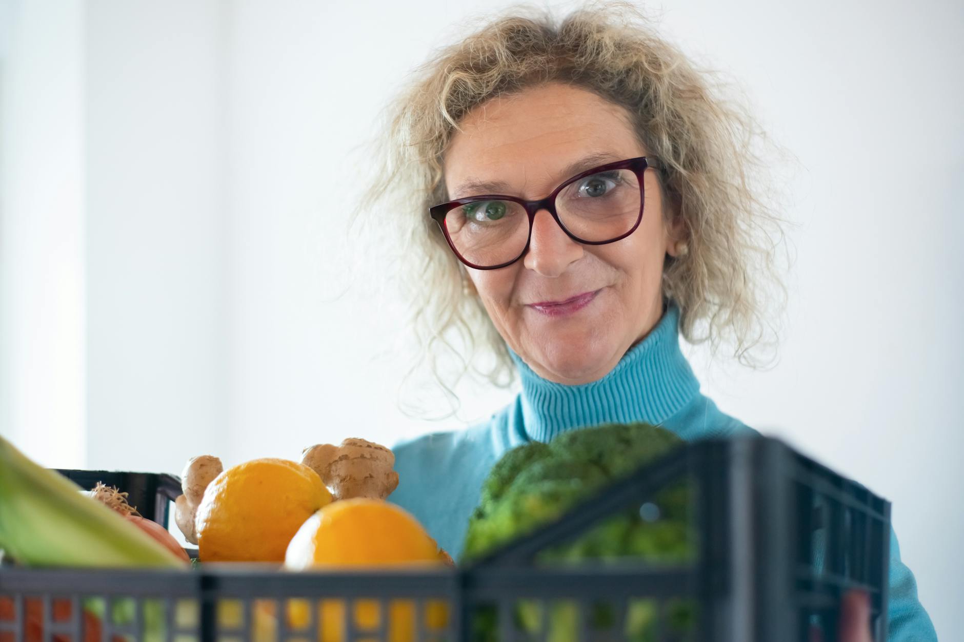 Elderly woman holding fresh fruit and vegetables, representing hearing-healthy nutrition