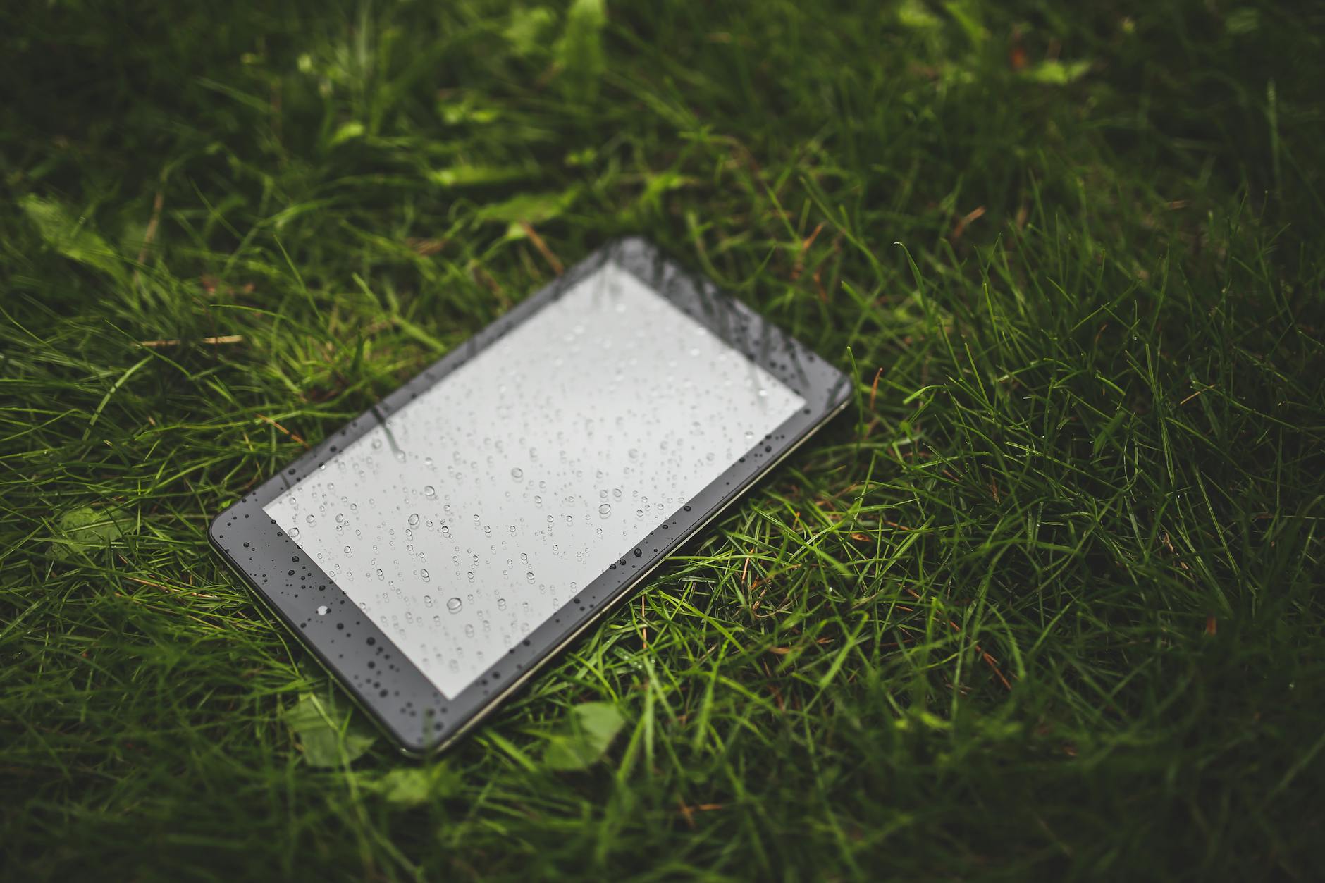 Understanding IP Ratings for Outdoor Electronics Tablet lying on wet grass with raindrops — illustrating the need to understand IP ratings for outdoor electronics