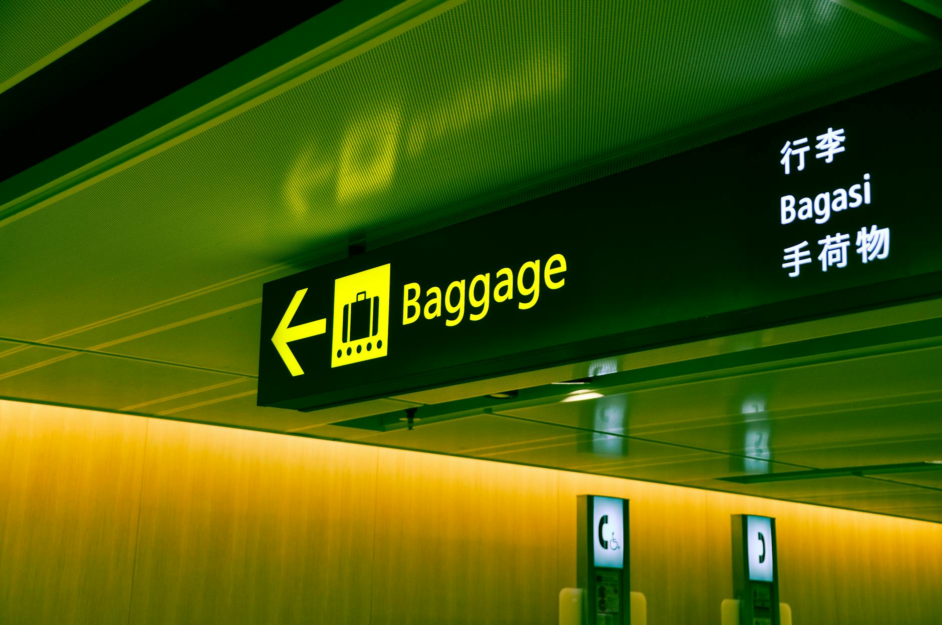 Illuminated multilingual airport baggage sign showing directions for international travelers