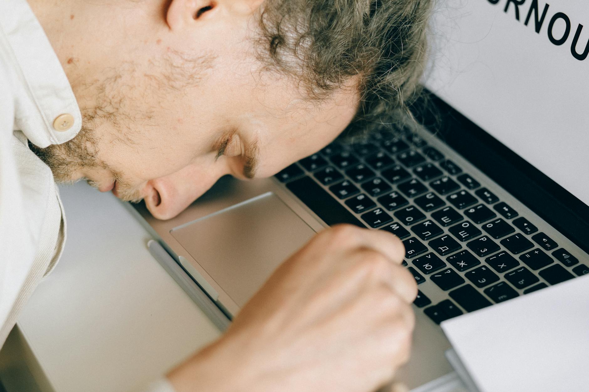 Persistent Fatigue — A Key Liver Health Warning Sign Exhausted woman resting her head on a desk, illustrating persistent fatigue as a liver health symptom