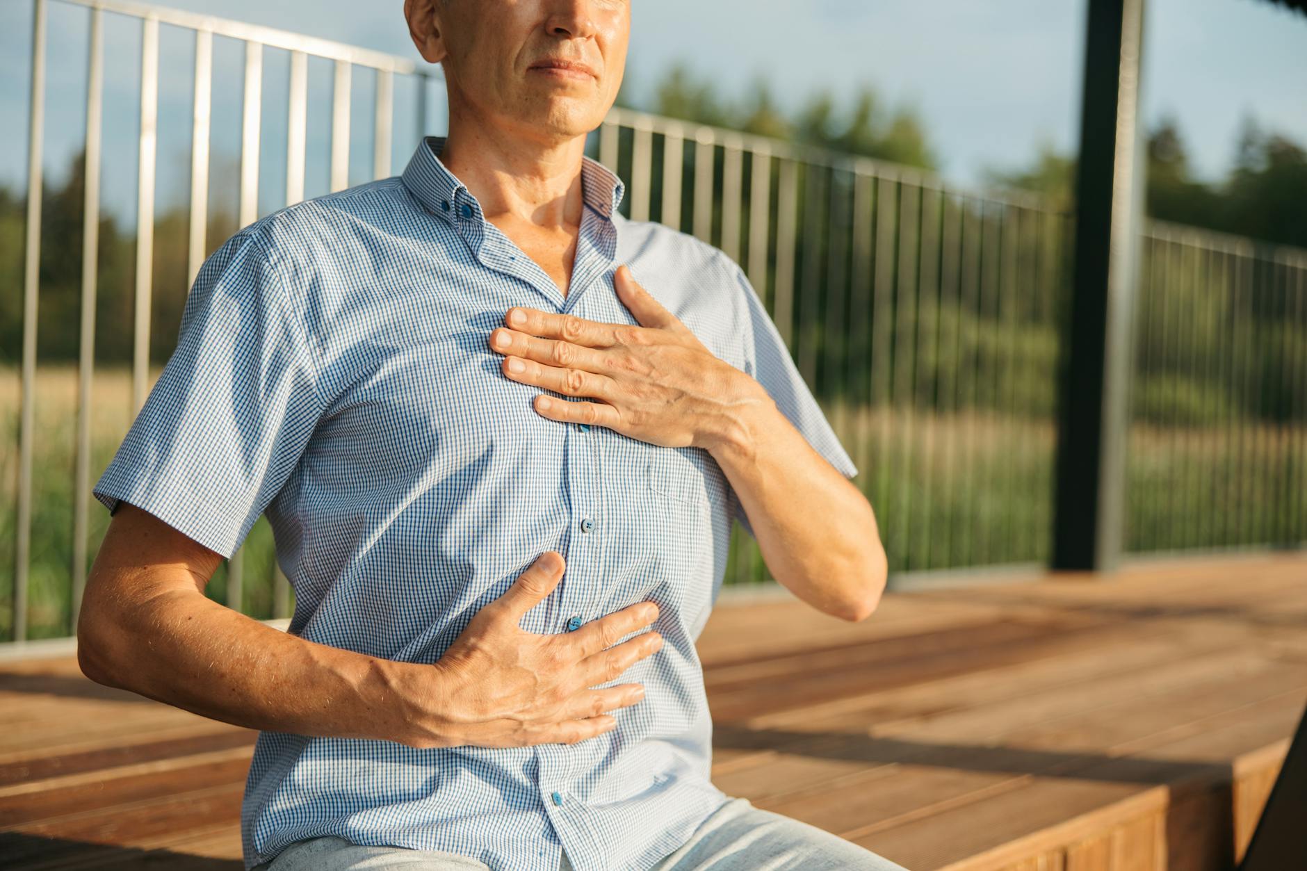 Man practicing deep breathing with hands on chest, a key exercise for lung recovery after quitting smoking
