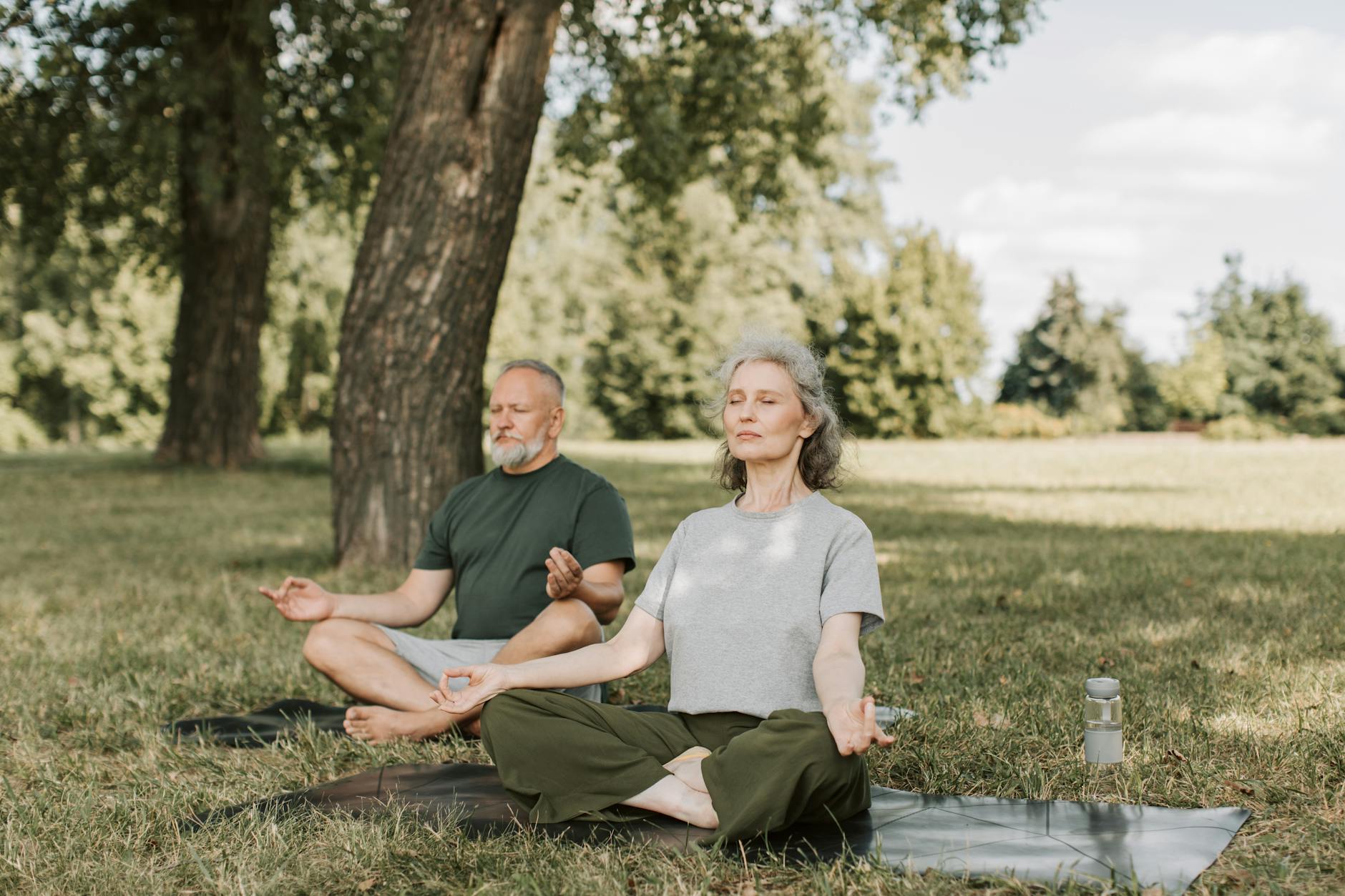 Senior couple meditating outdoors, representing long-term health recovery benefits after quitting smoking