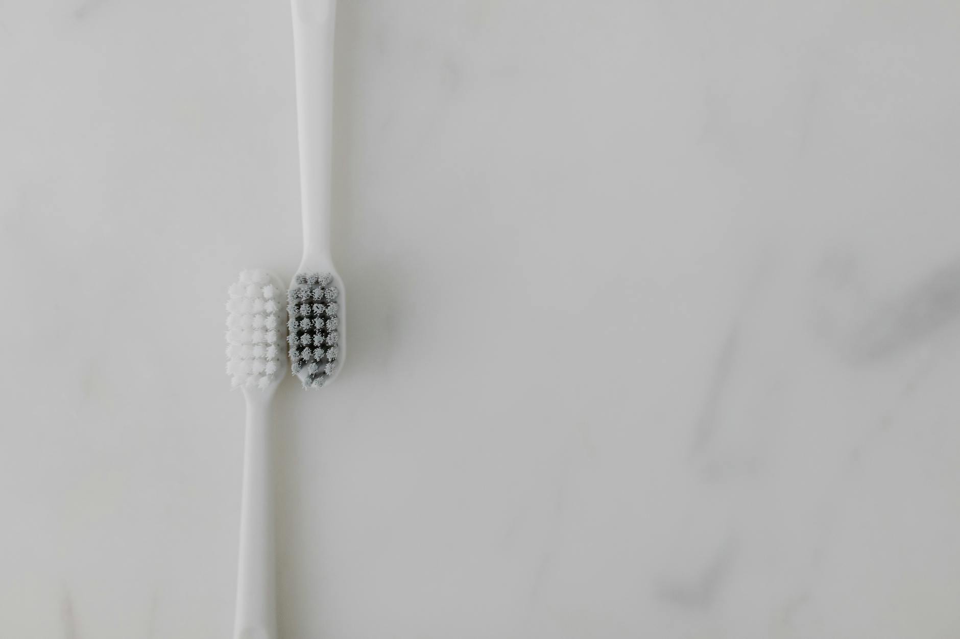 Manual vs Electric Toothbrush Side by Side 2026 Two toothbrushes side by side on a marble surface representing the manual vs electric toothbrush comparison