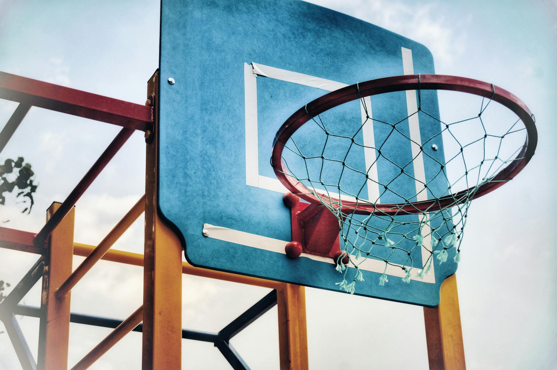 Basketball hoop viewed from below against a blue sky