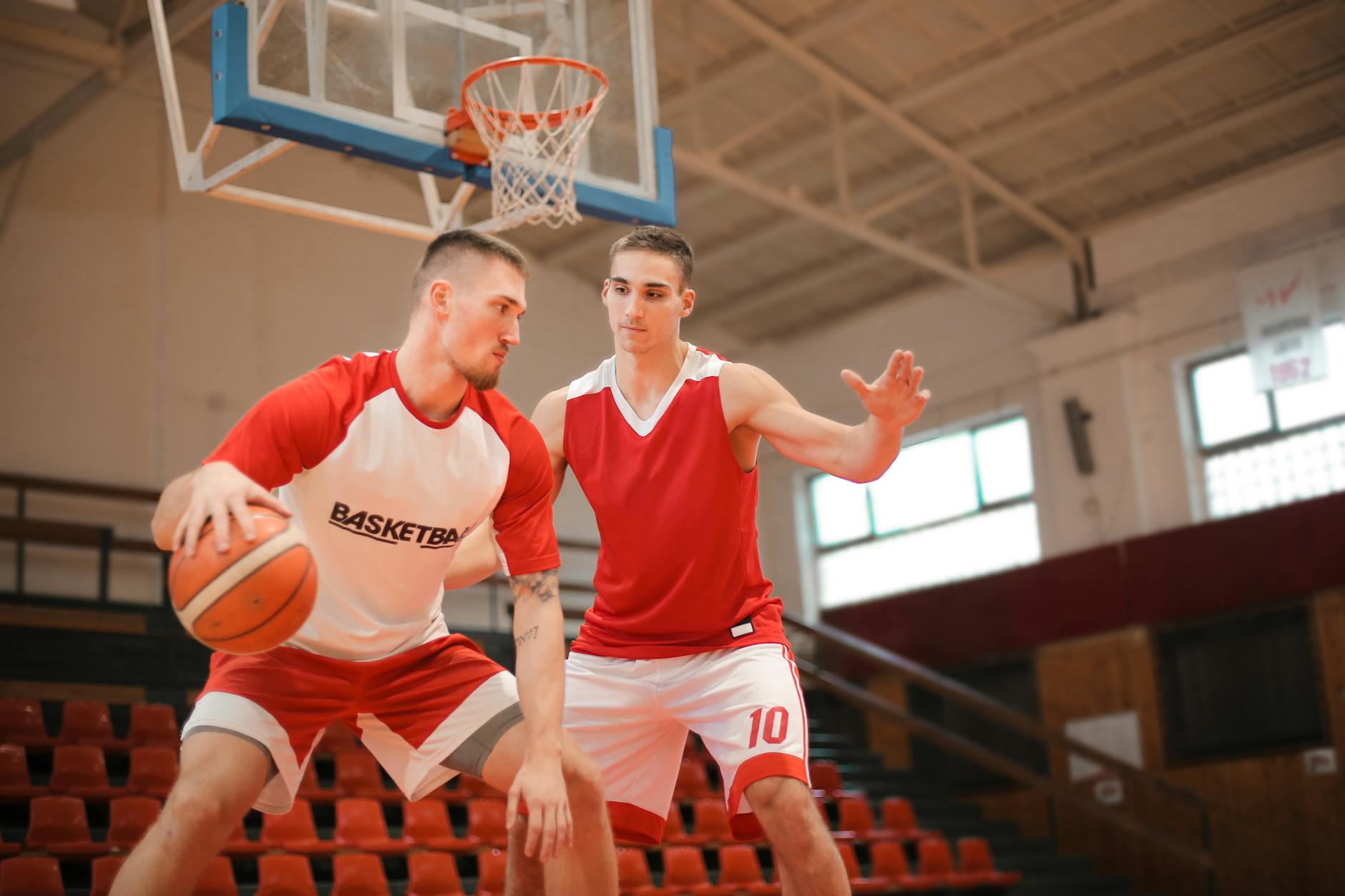 Two basketball players practicing passes and skills on an indoor court