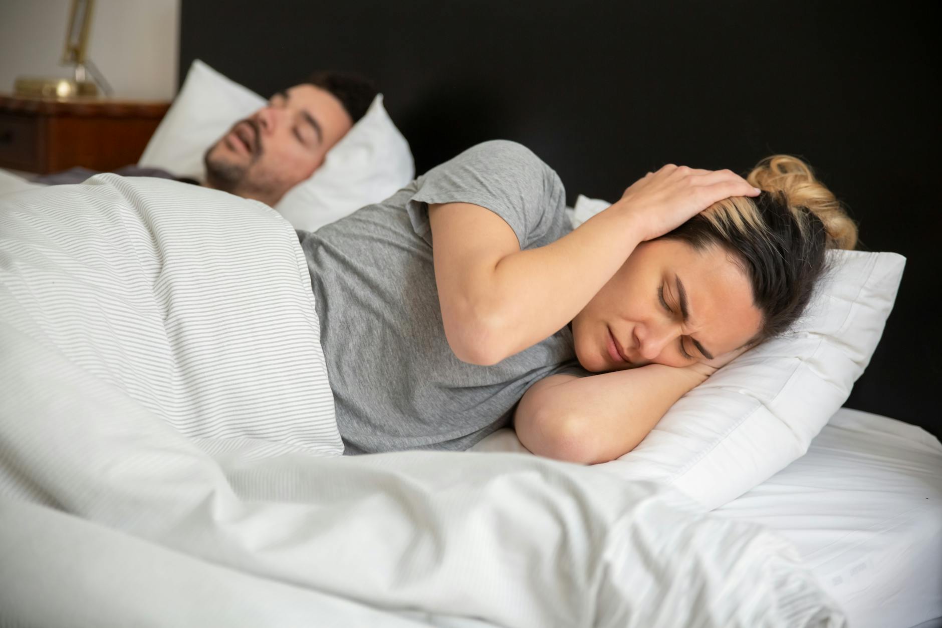 Woman lying awake in bed frustrated by noise disrupting her sleep