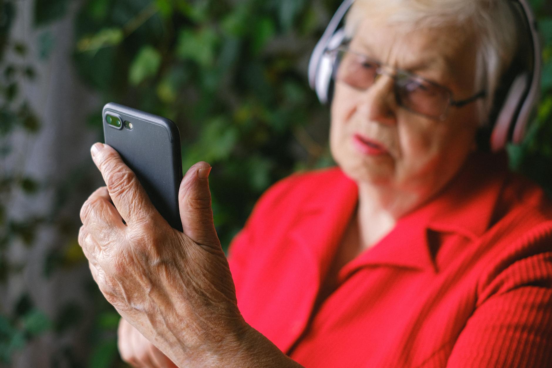 Senior woman outdoors using audio device to improve hearing