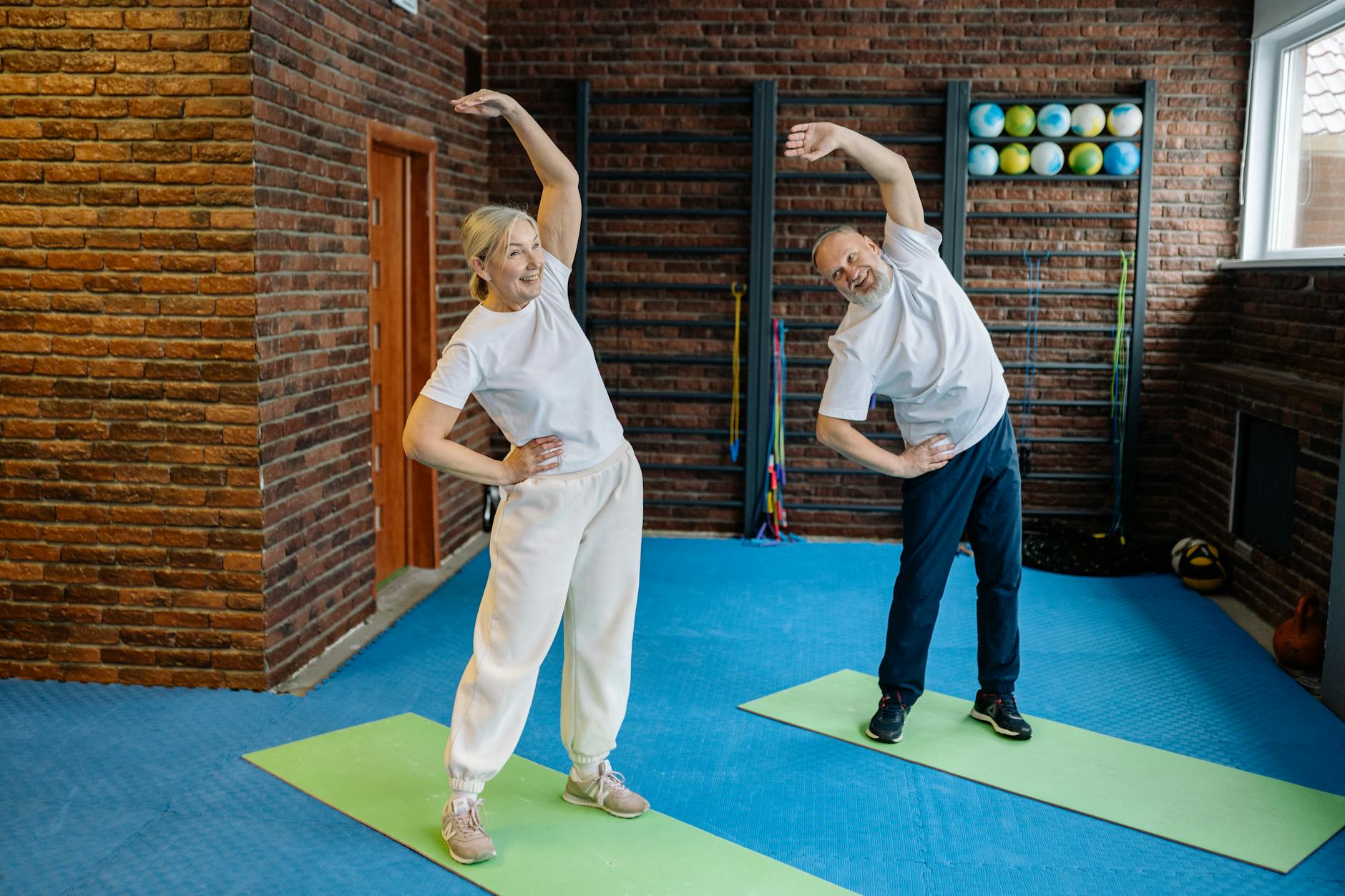 Elderly couple doing stretching exercises on yoga mats at home for joint pain relief