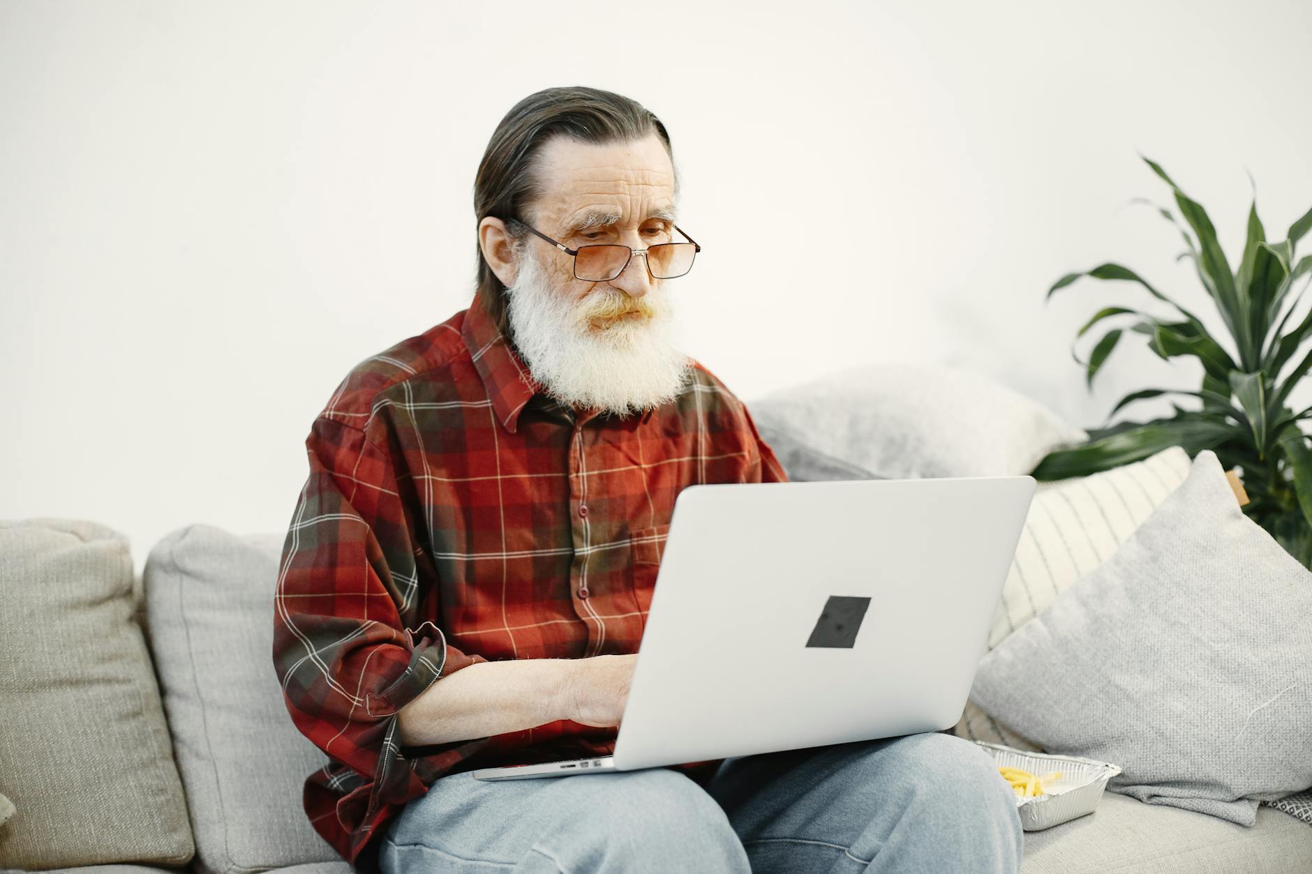 Older man using a laptop at home, representing everyday internet users targeted by phishing scams