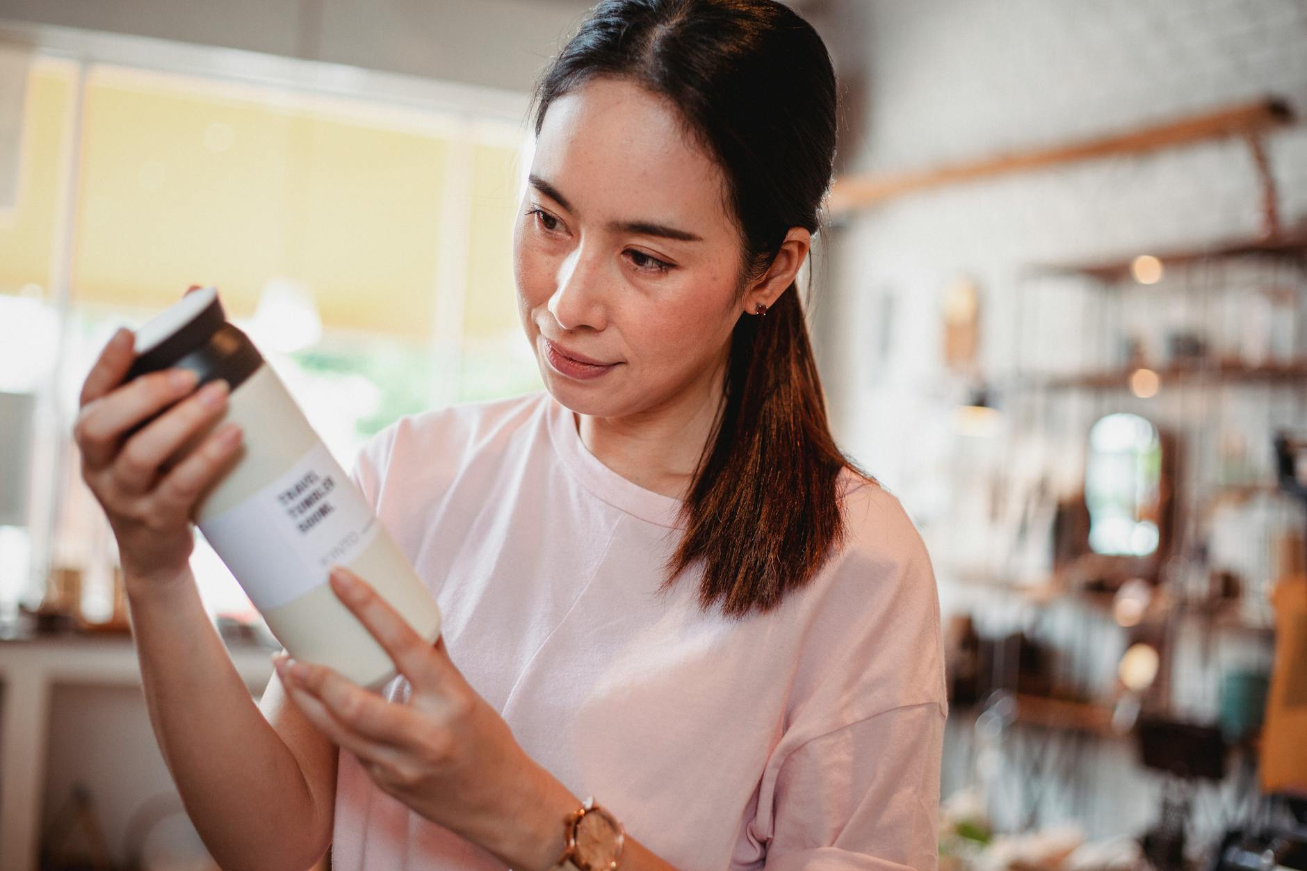 Person carefully reading ingredient label on a cosmetic product bottle in a store