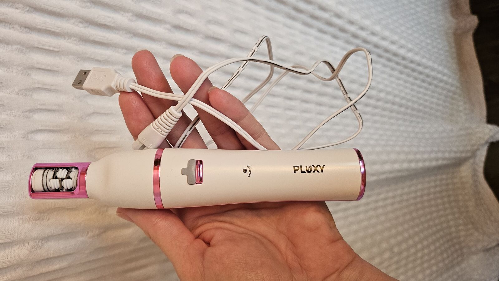 Hands holding Pluxy Epil Pro device and packaging during unboxing