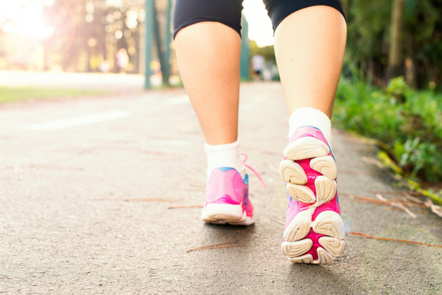 Woman walking outdoors in pink sneakers — regular walking is one of the best leg circulation exercises