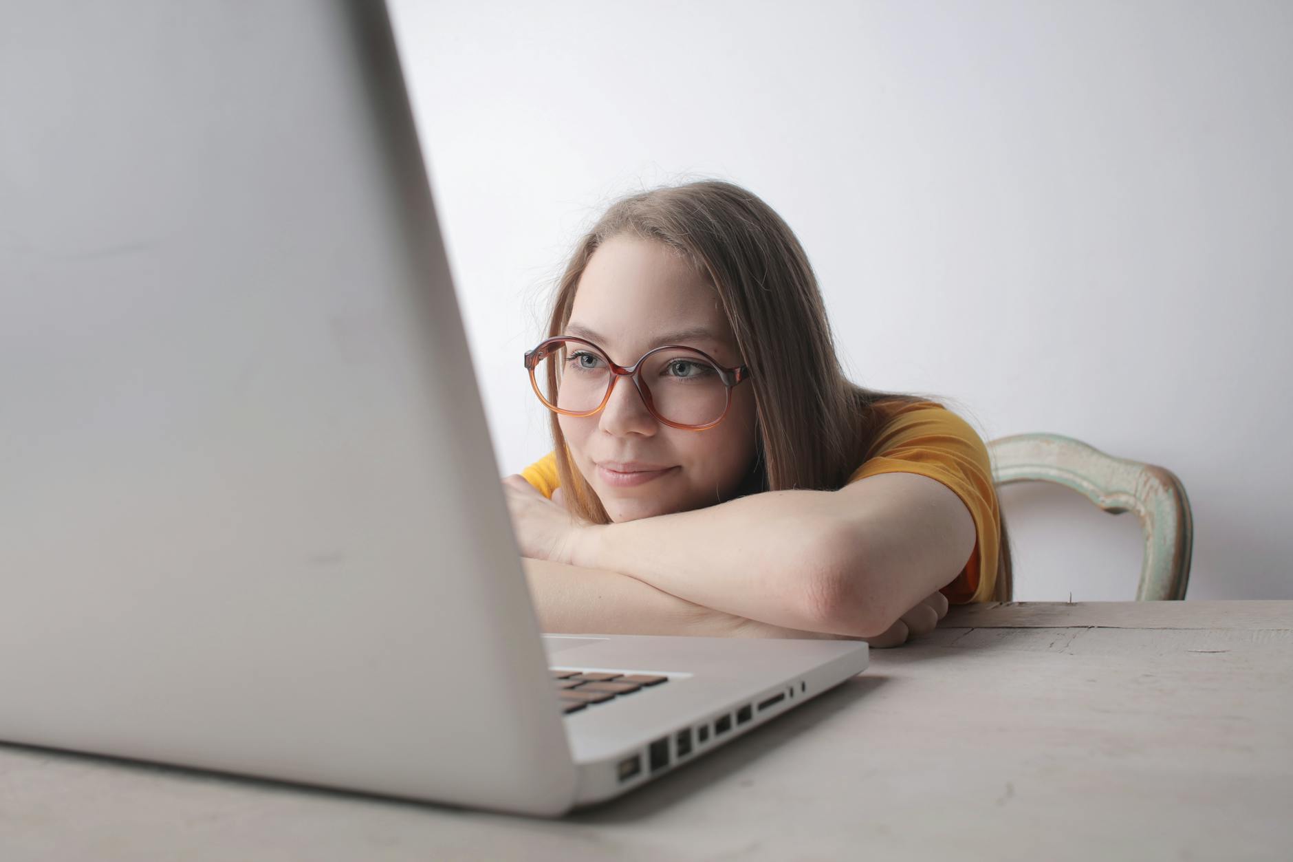 Woman sitting at a desk with a laptop, illustrating a sedentary lifestyle that contributes to poor leg circulation