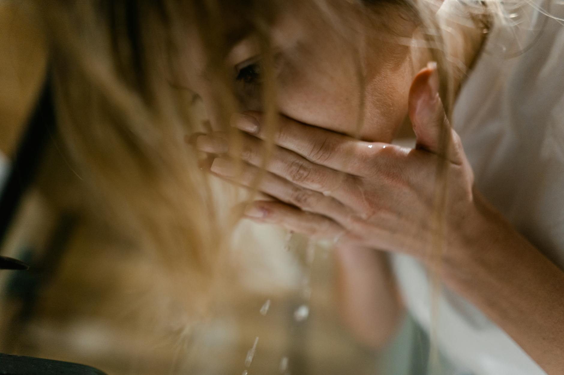 Woman splashing cold water on her face in the morning to reduce eye puffiness and swelling
