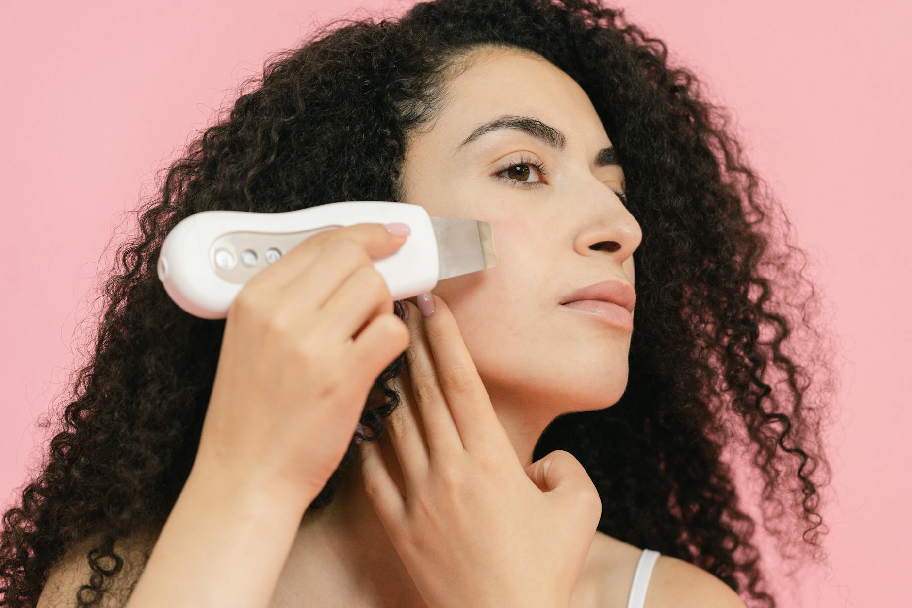 Woman using a handheld skincare device on her face as part of a home skincare routine