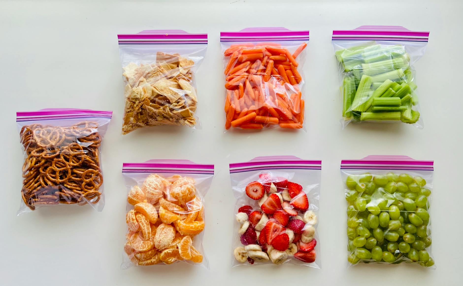 Fruits, vegetables, and snacks packed neatly in organized zip-lock bags for travel