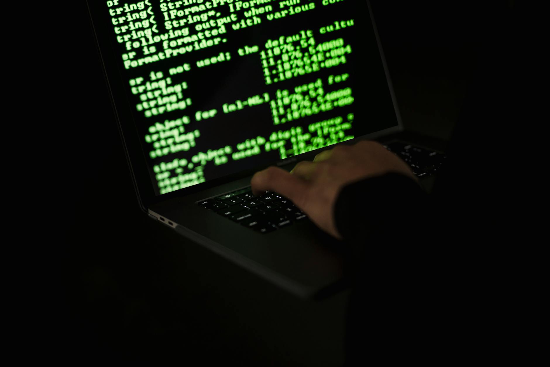 Hacker typing on a laptop in the dark — illustration of cybercrime and malware threats