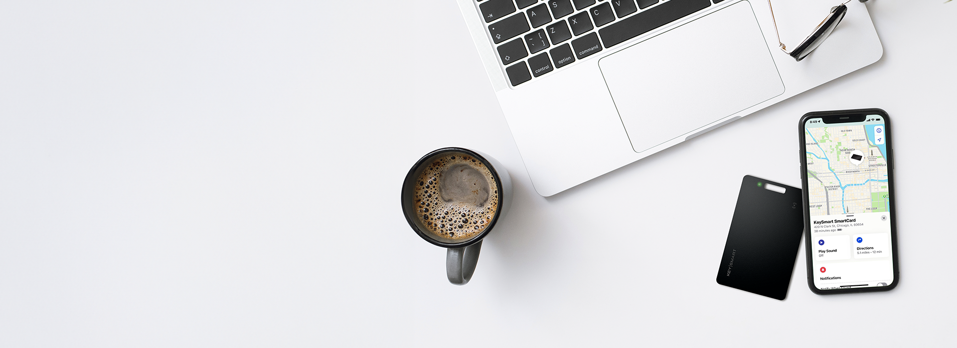 Person holding the SmartCard by KeySmart alongside a smartphone showing Apple Find My app
