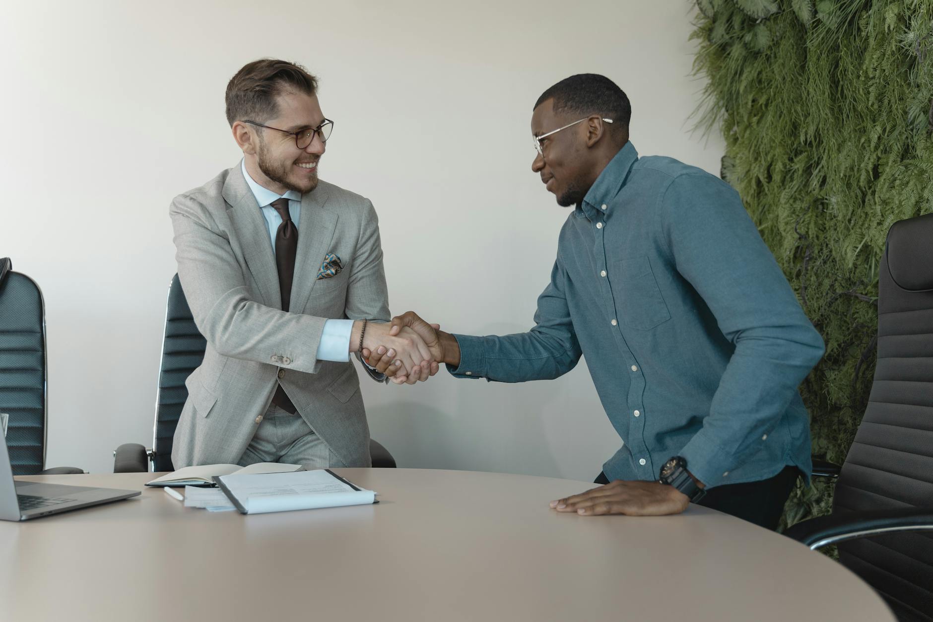 Two professionals shaking hands after a successful job interview, illustrating how smile confidence psychology affects career outcomes