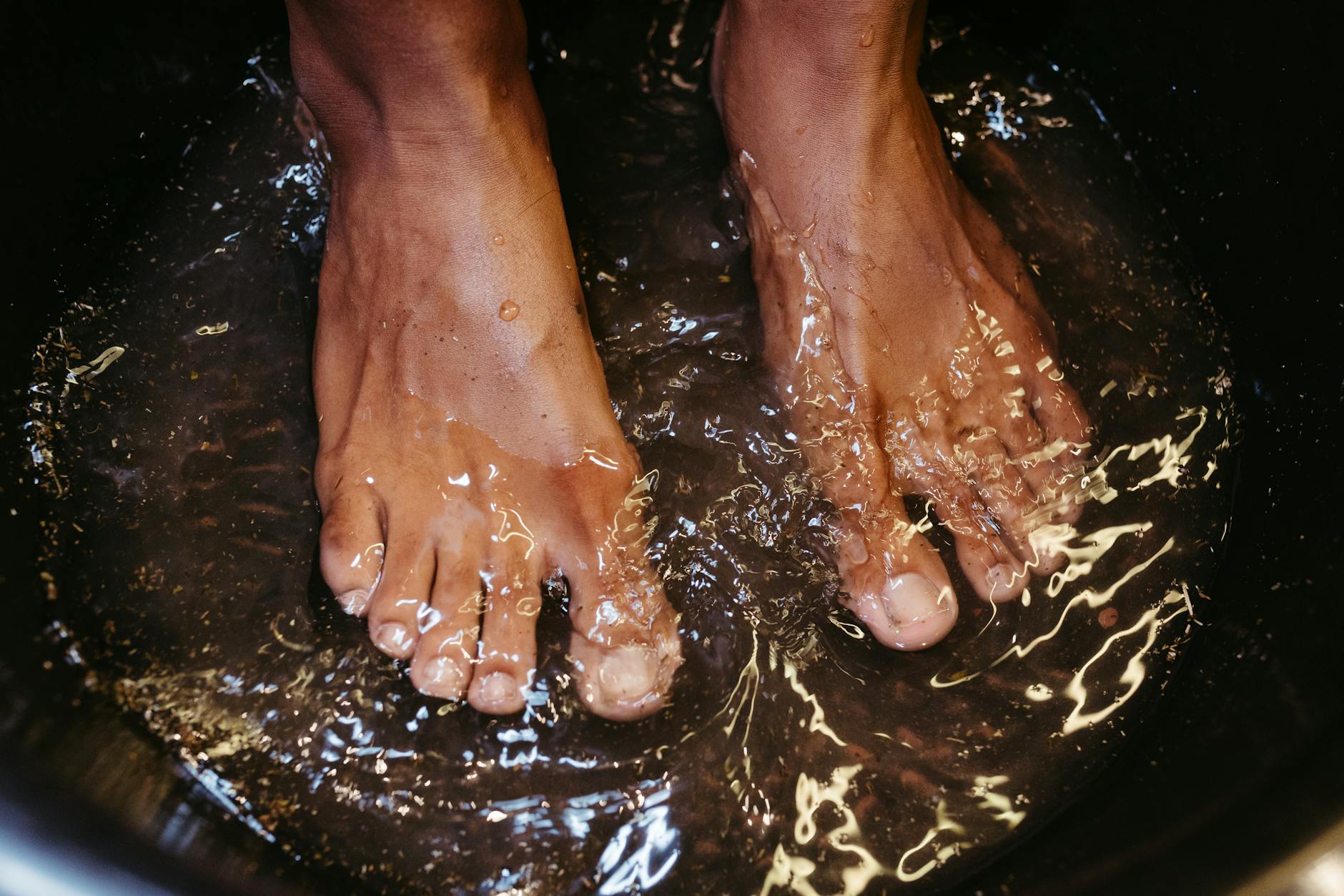 Foot Soak Recovery After Standing All Day Close-up of tired feet soaking in water for post-shift recovery