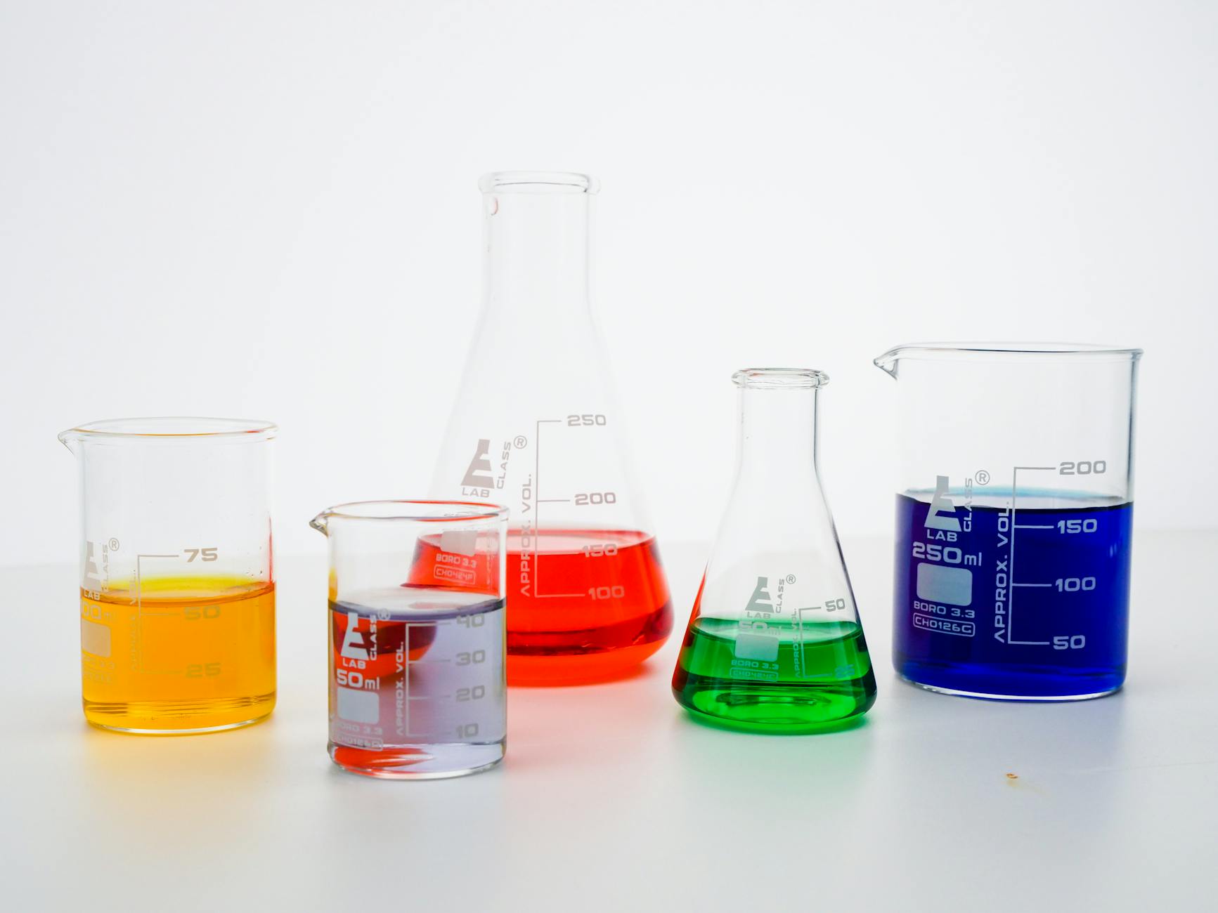 Colored liquid solutions in laboratory beakers representing chemical whitening ingredient research