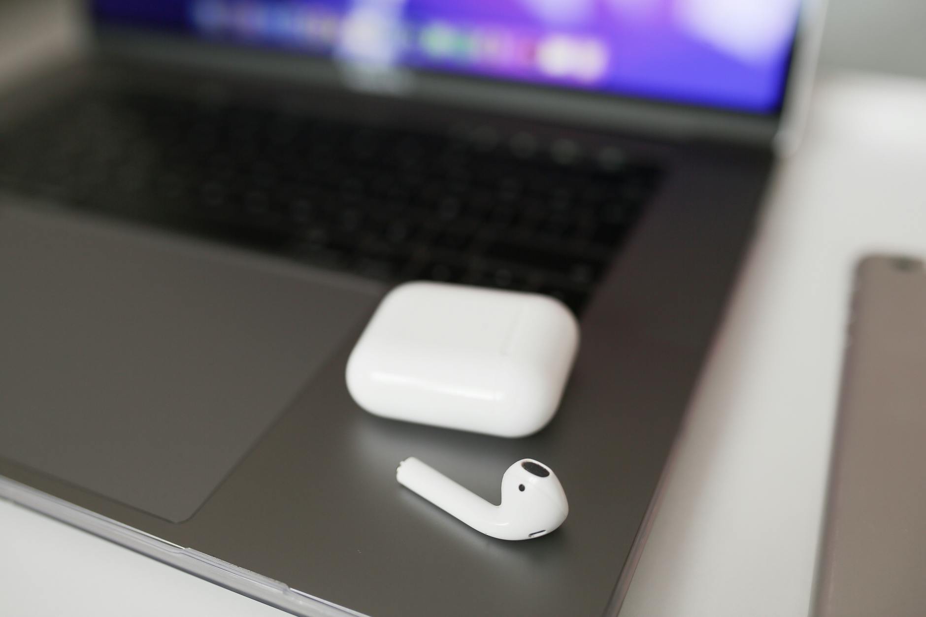 Wireless earbuds in their case resting on a laptop — a must-have travel tech gadget for international trips
