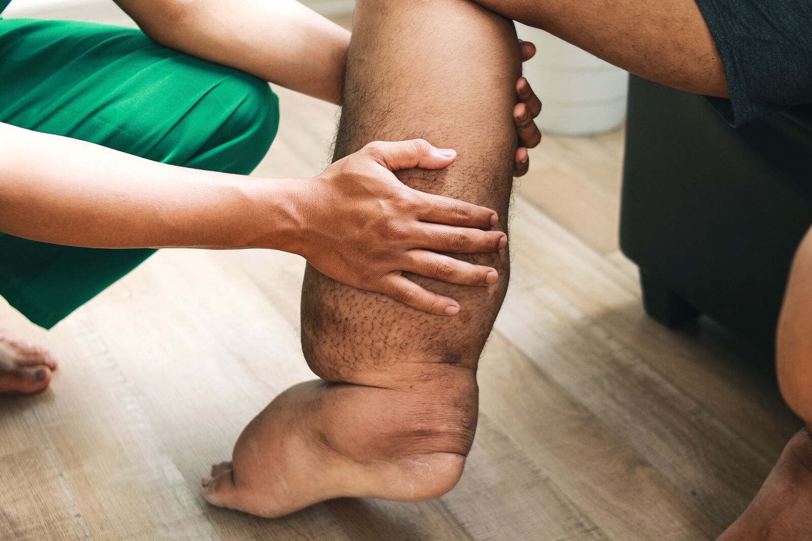 Person using TheraFoot Pro EMS foot massager while standing on mat with blue LED activated