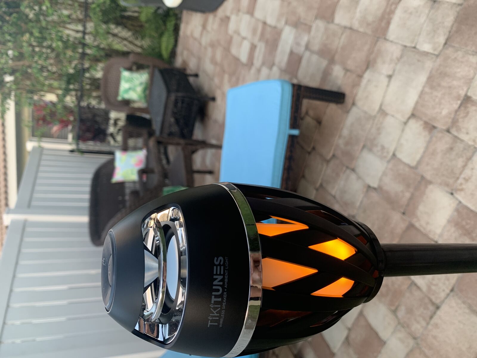 TikiTunes Bluetooth Speaker being held in backyard rain, demonstrating IP65 waterproof water resistance