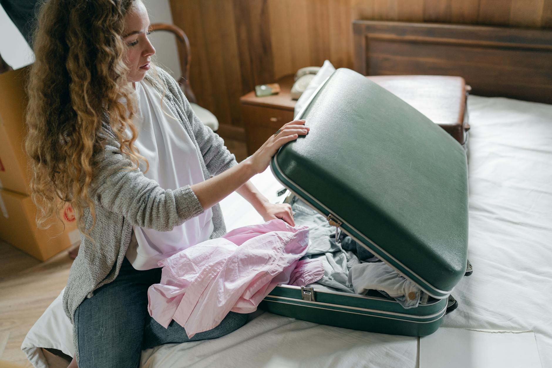 Strategic Packing for Travel Security Woman carefully packing a suitcase in her bedroom before travel