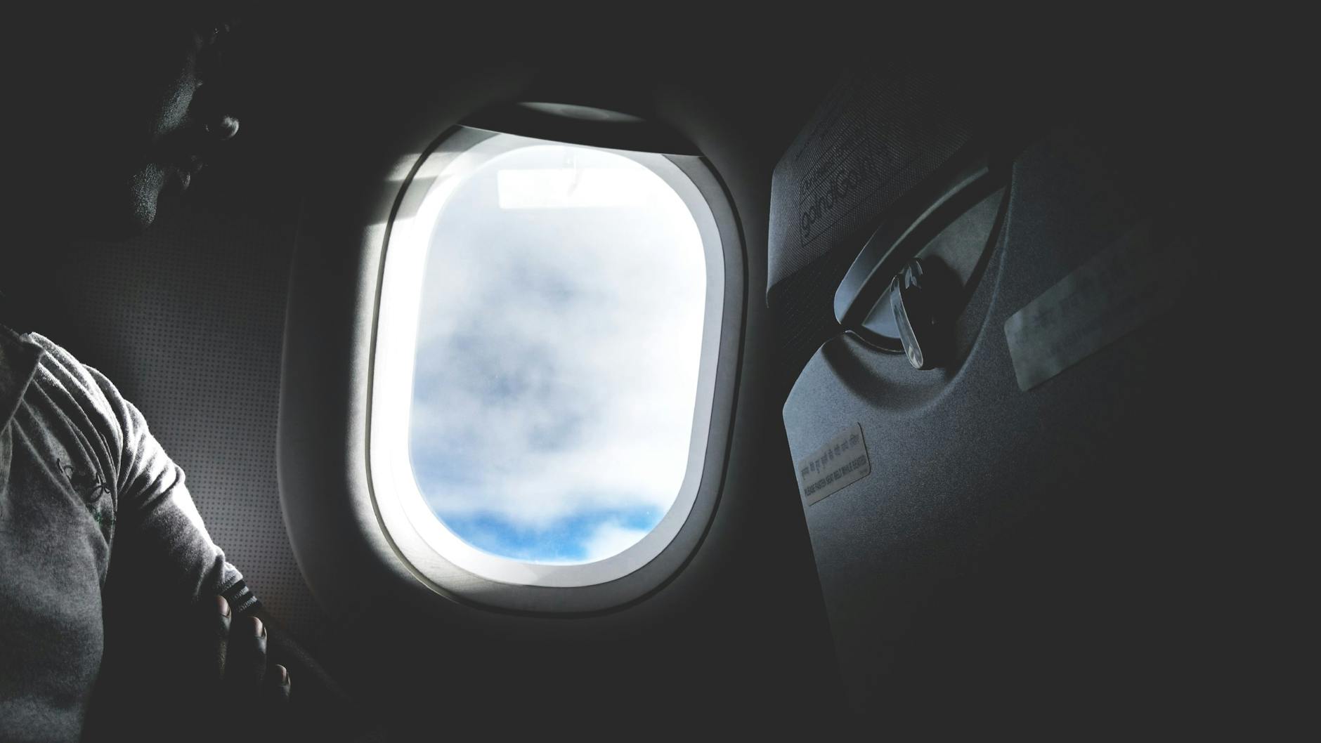 Travel Tech Packing List 2026 - Long-Haul Flight Passenger looking out airplane window during flight