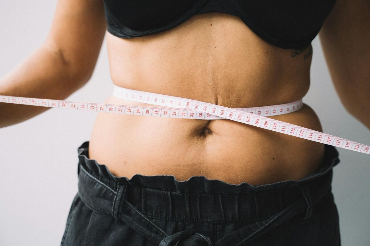 Waist Circumference Measurement for Visceral Fat Assessment Person measuring waist circumference with a tape measure — a key indicator of visceral fat levels