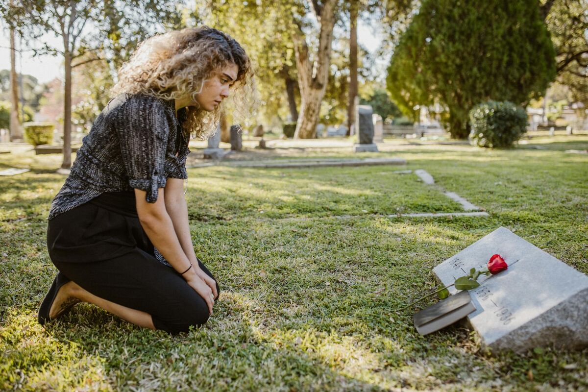 Family Grief and Loss - The Emotional Toll of Unpreparedness A person grieving at a cemetery, representing the emotional weight families carry after unexpected loss