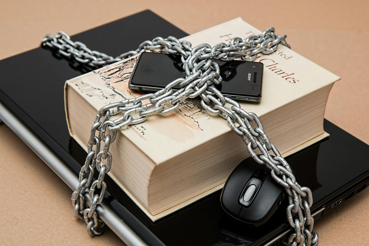 Chain-locked book, phone, and laptop symbolizing the importance of securing personal digital information