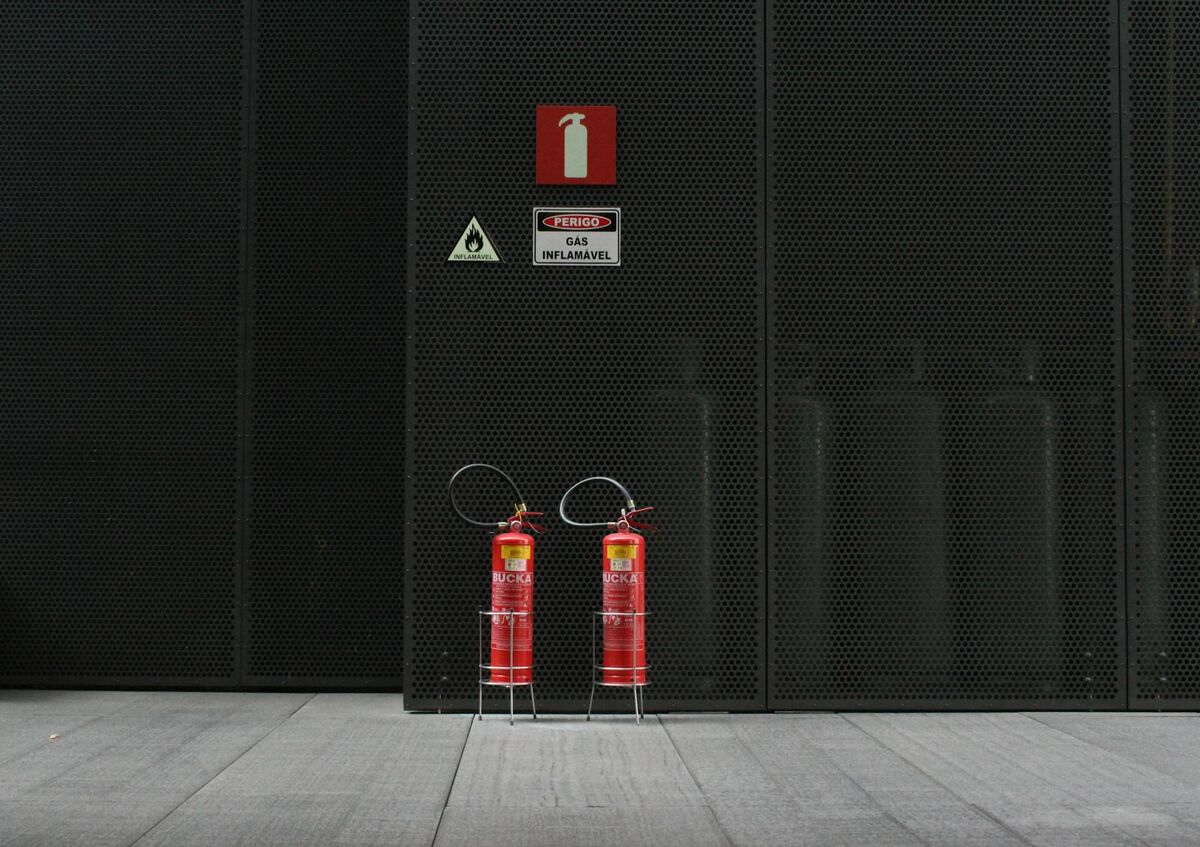 Red fire extinguishers mounted on an industrial wall — fire blankets are an alternative first-response tool alongside extinguishers