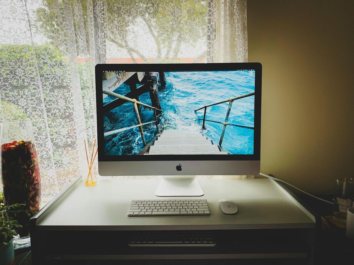 Modern home office computer desk setup by a window showing a connected workspace