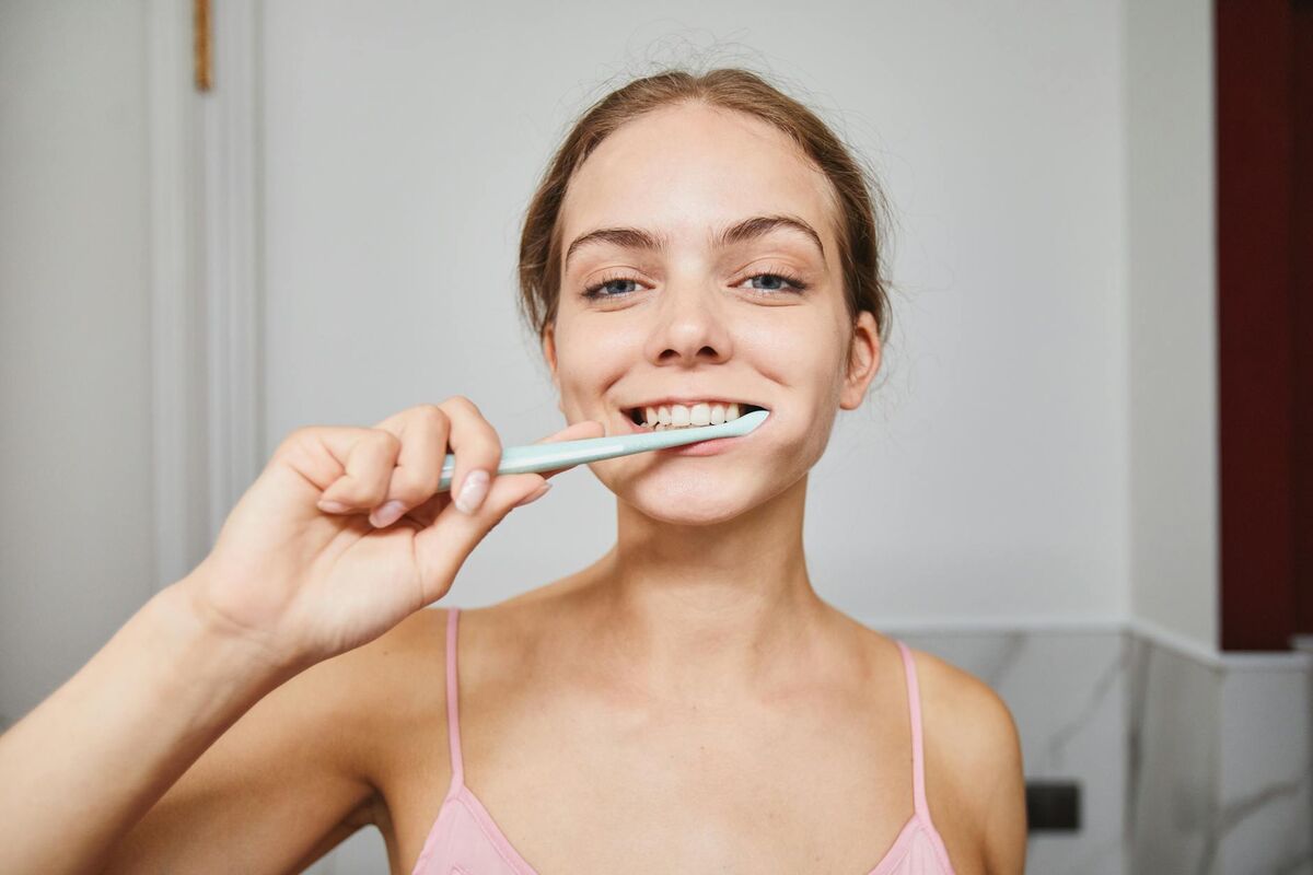 Close-up of a woman smiling while brushing her teeth in a modern bathroom