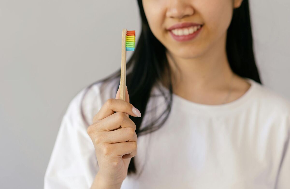 Woman smiling and holding a toothbrush, practicing good dental hygiene