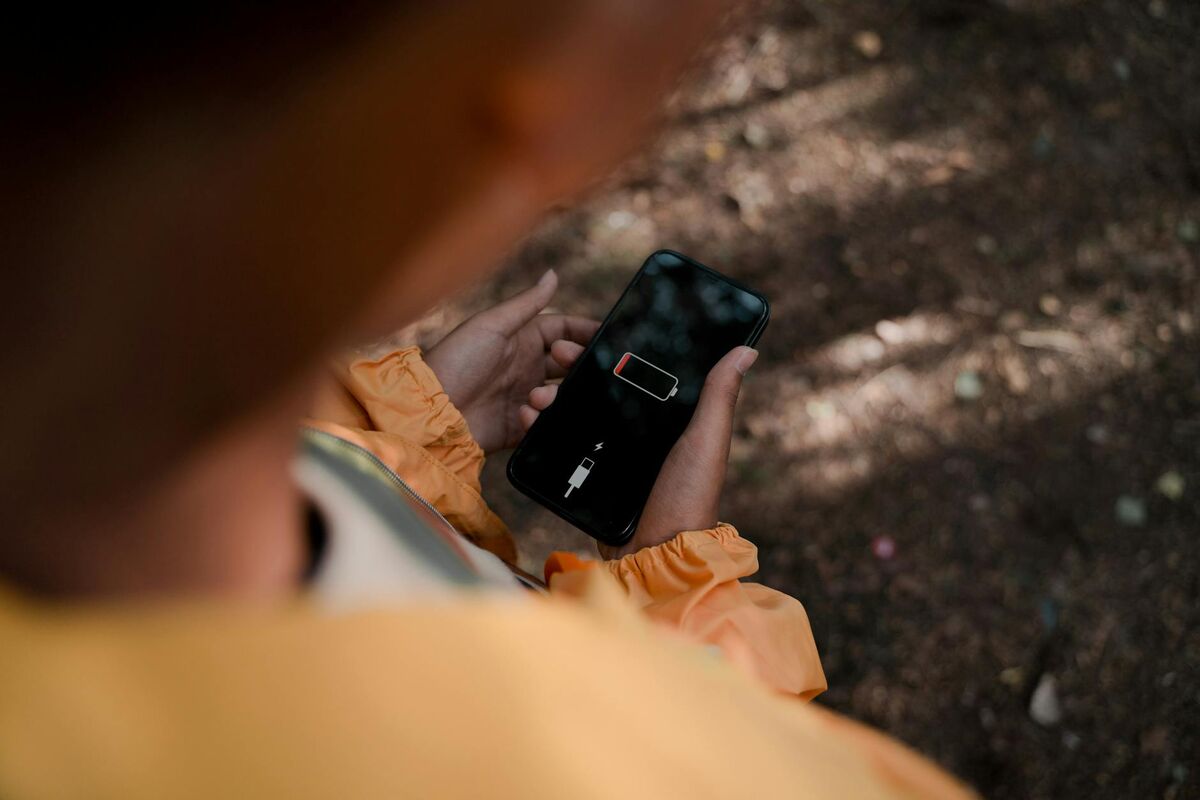 Low Battery Warning on Smartphone Outdoors Young person holding a smartphone showing low battery warning outdoors in natural light