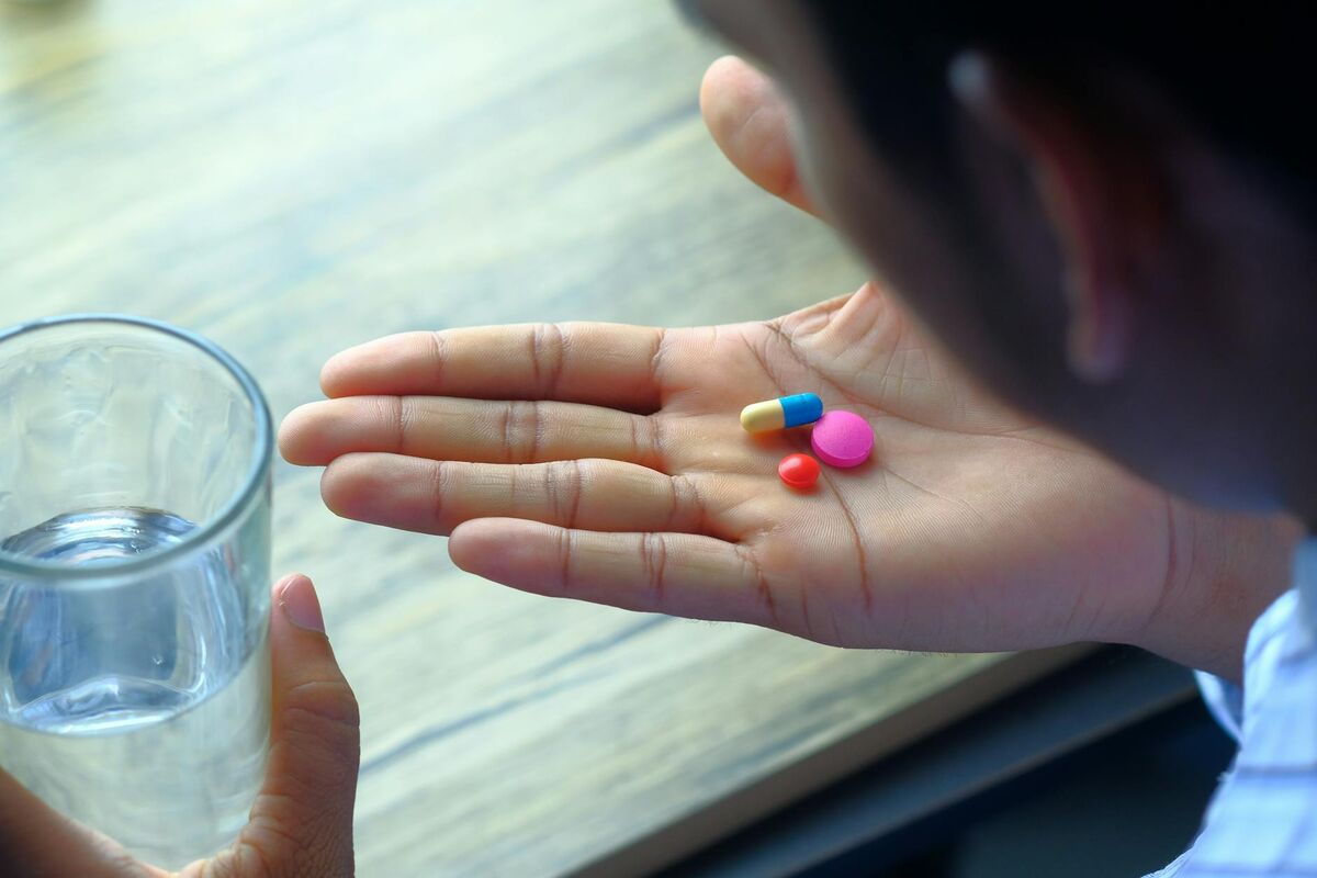 Daily Supplement Routine for Gut Health Hand holding supplement capsules alongside a glass of water for daily gut health routine
