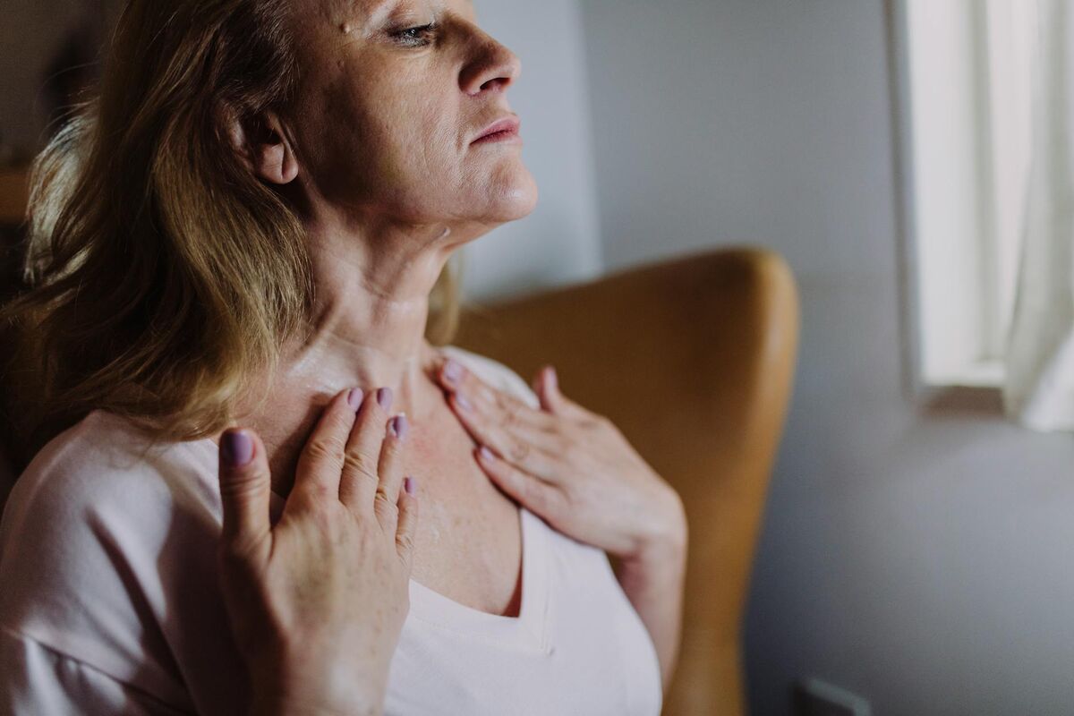 Mature woman massaging moisturizer into her neck as part of a firming skincare routine