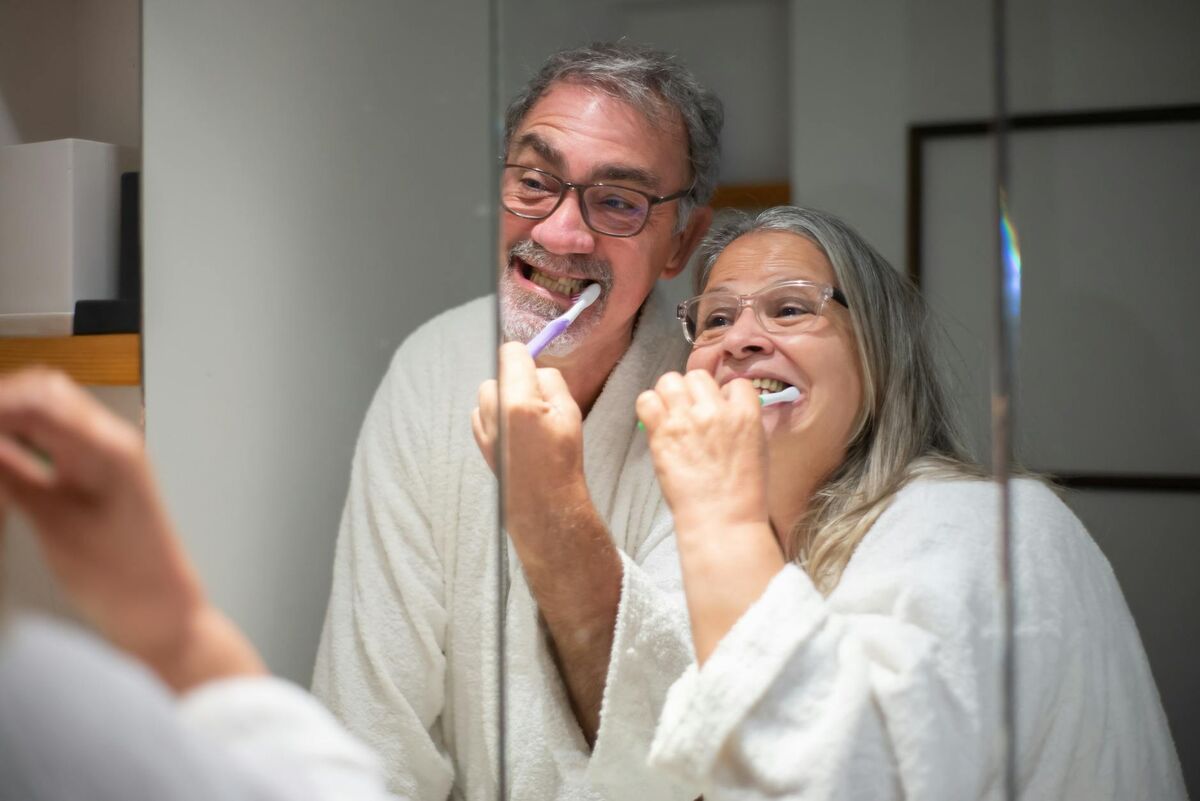 Senior couple brushing their teeth together in front of a bathroom mirror