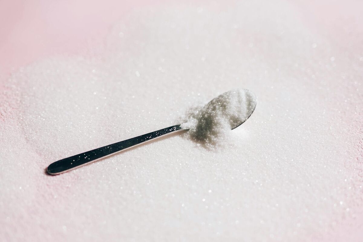 White spoon with sugar-like white powder representing xylitol sweetener